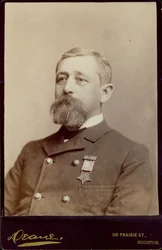 Retrato busto de Alfred K. Taylor, girado a la izquierda, y vistiendo una chaqueta de doble botonadura con una medalla prendida